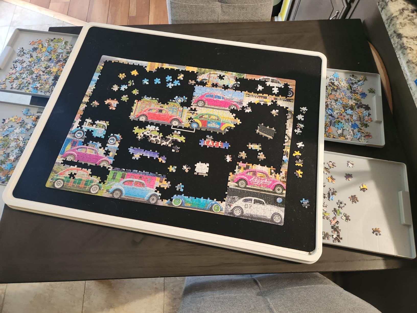 Playboda puzzle board with drawers and sorting trays holding a colorful car jigsaw puzzle in progress