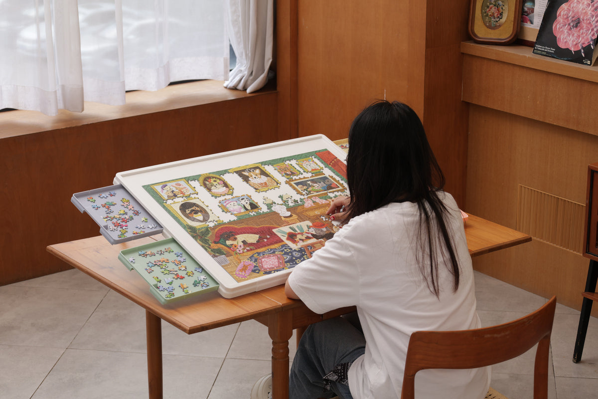Woman puzzling with Playboda tilting jigsaw puzzle board and sorting trays on a wooden desk