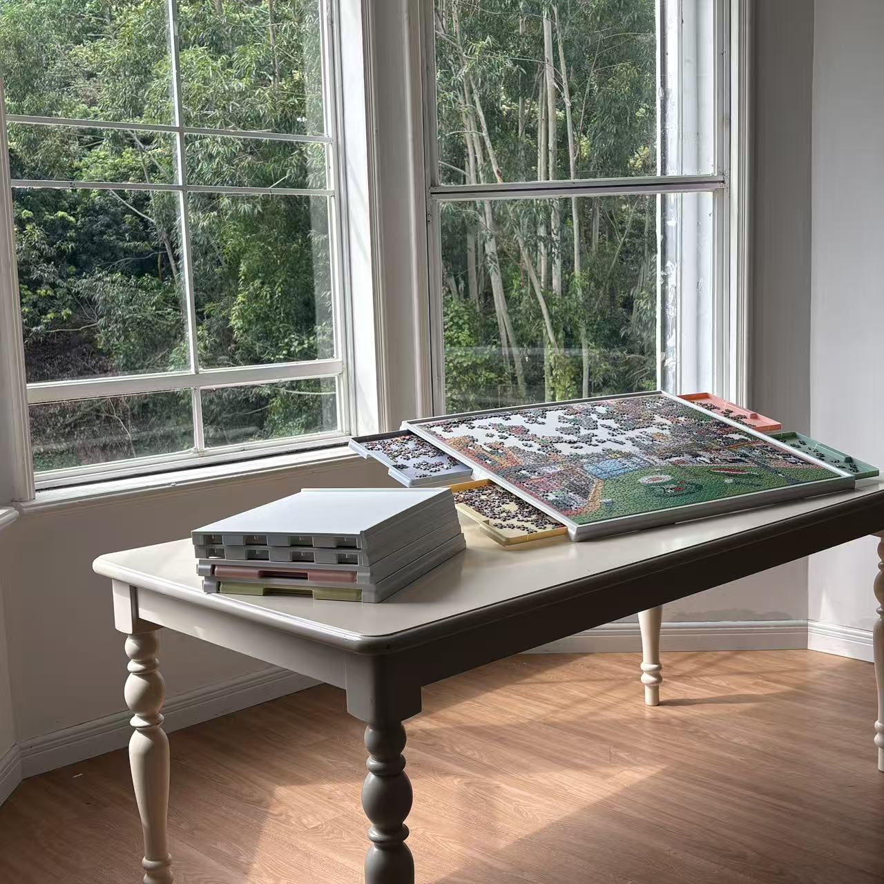 Playboda puzzle board with drawers and sorting trays placed on a wooden table by the window