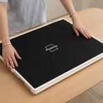 Playboda puzzle board stored under a sofa with protective cover, showing its slim profile and space-saving design for easy storage between puzzle sessions.