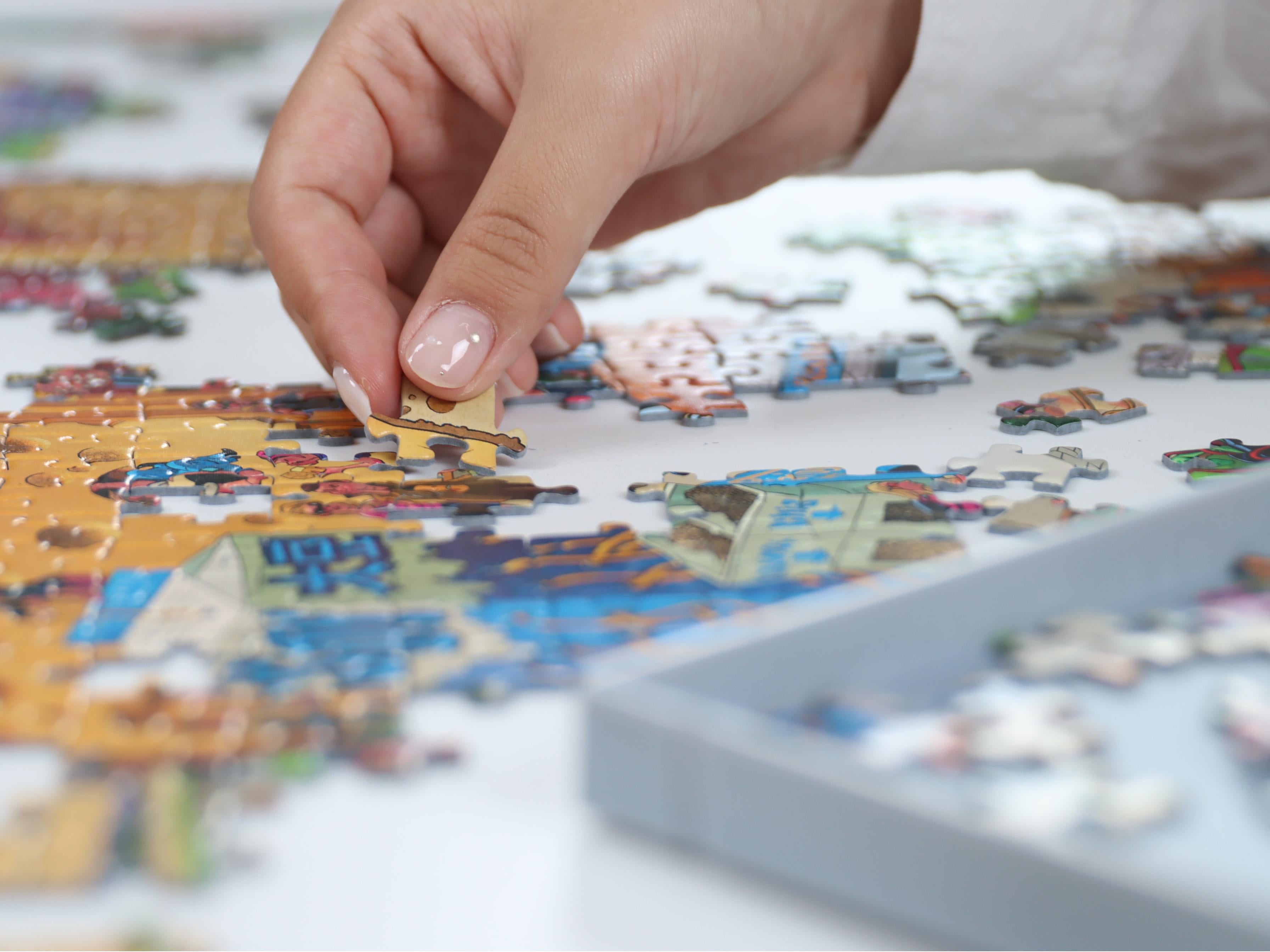 Close-up of a hand placing a puzzle piece onto a colorful cartoon-style jigsaw puzzle