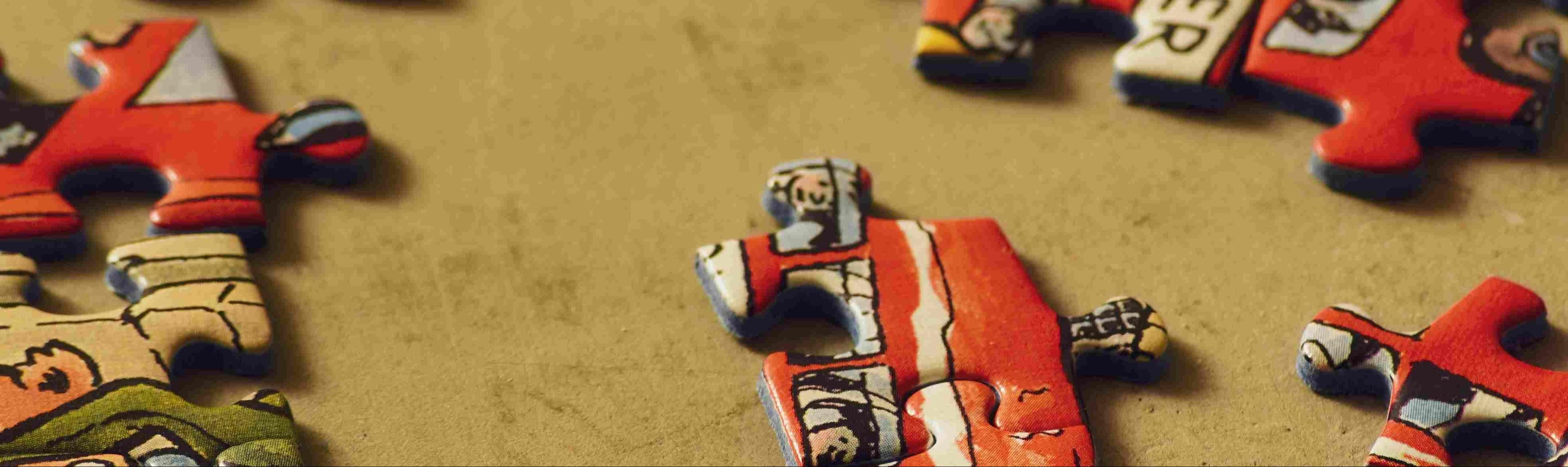 Close-up of colorful jigsaw puzzle pieces on a warm textured surface, background image for Playboda email subscription section